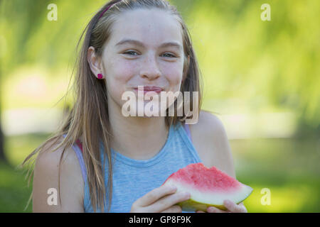 Portrait of happy Hispanic teen girl eating watermelon Stock Photo