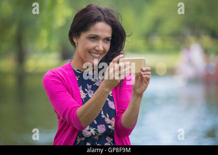 Happy Hispanic woman using her mobile phone in a park Stock Photo