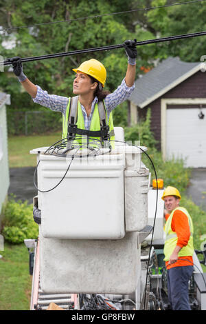 Hispanic female cable lineman examining the cables in the rain Stock Photo
