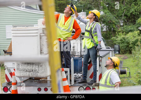 Utility workers looking at the line work in the rain Stock Photo