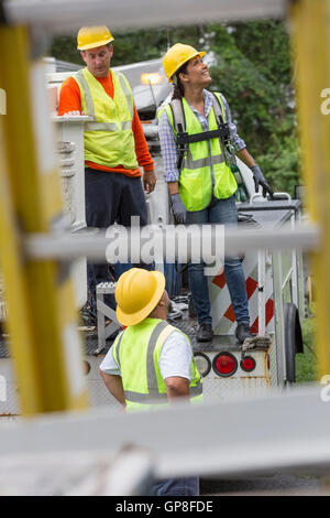 Utility workers looking at the line work in the rain Stock Photo