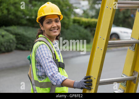 Portrait of happy Hispanic female lineman working on power line at site Stock Photo