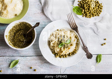 Pasta (spaghetti), green beans, sauce pesto, parmesan, fresh basil. Vintage plates, wooden table, top view. Stock Photo