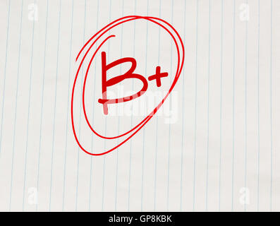 B plus (B+) grade written in red on notebook paper Stock Photo