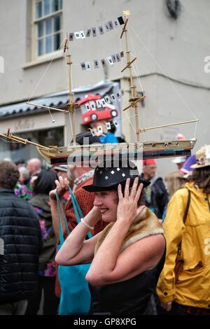 Bridport, Dorset, UK. 3rd September 2016. A woman balances a ship hat on her head as thousands of hat wearers gather and promenade in Bridport during the seventh Annual Hat Festival. The Festival encourages residents and visitors to take part in hat related activities and and competitions including including most fun hat, best hatted dog, and most elegantly-hatted couple. Credit:  Tom Corban/Alamy Live News Stock Photo