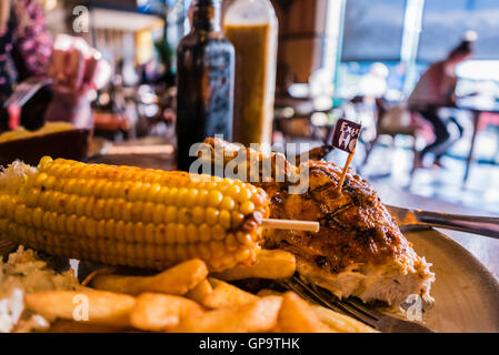 Extra hot chicken, chips and corn-on-the-cob on a table in a Nando's restaurant