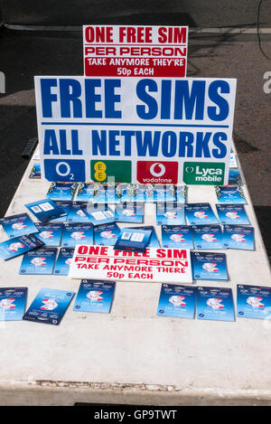 Free SIM cards for mobile phones on a market stall, with sign advising people to take one per person, including grammatical erro Stock Photo