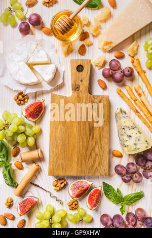 Cheese and Fruits Assortment on Cutting Board with Red, White Wine on  Wooden Background. Stock Photo by annapustynnikova