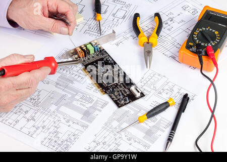 Electronics engineer soldering a component onto an intergrated computer card Stock Photo