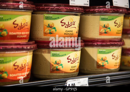 Containers of Sabra brand hummus stacked on a shelf at a grocery store. Stock Photo