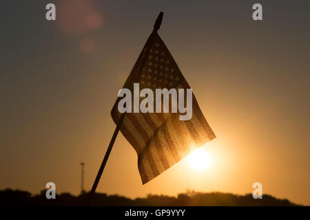 The sun rises behind an American Flag flying outside a cabin on Little Pine Lake near Aitkin, Minnesota, USA August  25, 2016 Stock Photo