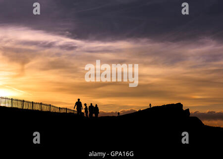 Holidaymakers seen in silhouette as a spectacular sunset breaks over Porth Island in Newquay. Stock Photo