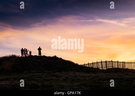 Holidaymakers in silhouette watch a spectacular sunset break over Porth Island in Newquay, Cornwall. Stock Photo