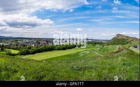 Panoramic summer view across Holyrood Park with Salisbury Crags looming over Edinburgh Scotland with the Castle on the horizon Stock Photo