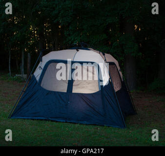 Last slivers of light coming through the forest at a lit tent Stock Photo
