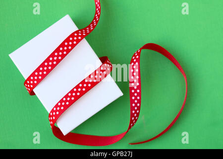 Small Christmas gift box and ribbon on green background Stock Photo