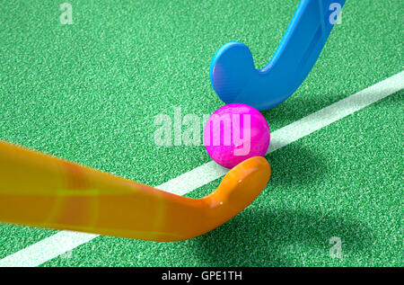 A 3D rendering of two hockey sticks standing opposite each other over a ball on green astro turf in the daytime Stock Photo