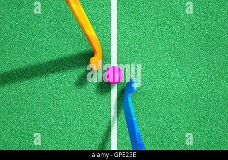 A 3D rendering of two hockey sticks standing opposite each other over a ball on green astro turf in the daytime Stock Photo