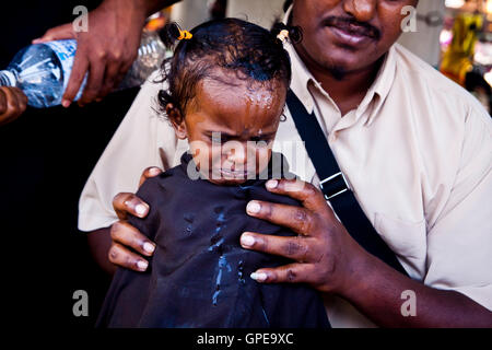 A young girl prepares to have her head shaved at the Thaipusam festival, Batu Caves, Malaysia. Stock Photo