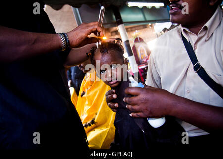 A young girl cries as she has her head shaved at the Thaipusam festival, Batu Caves, Malaysia. Stock Photo