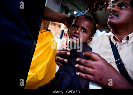 A young girl cries as she has her head shaved at the Thaipusam festival, Batu Caves, Malaysia. Stock Photo