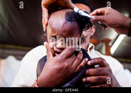 A young girl cries as she has her head shaved at the Thaipusam festival, Batu Caves, Malaysia. Stock Photo