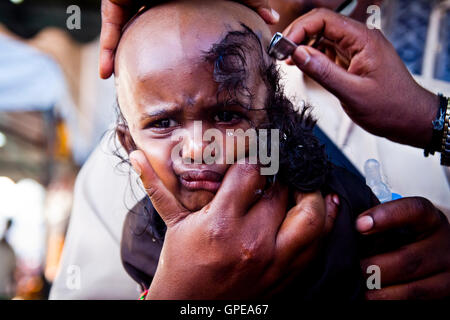 A young girl cries as she has her head shaved at the Thaipusam festival, Batu Caves, Malaysia. Stock Photo