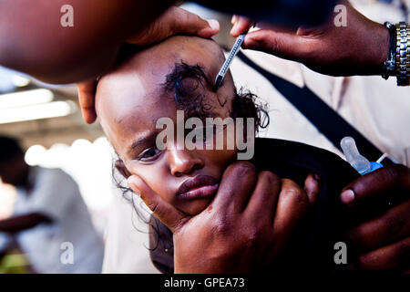 A young girl cries as she has her head shaved at the Thaipusam festival, Batu Caves, Malaysia. Stock Photo