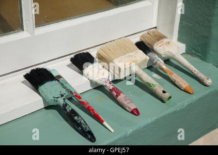 Used Paint brushes lined up on a windowsill. Stock Photo