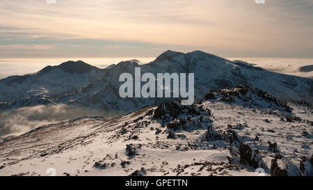 A wintery Snowdon massif, viewed above a cloud inversion from neighbouring Glyder Fawr, Snowdonia National Park, North Wales Stock Photo