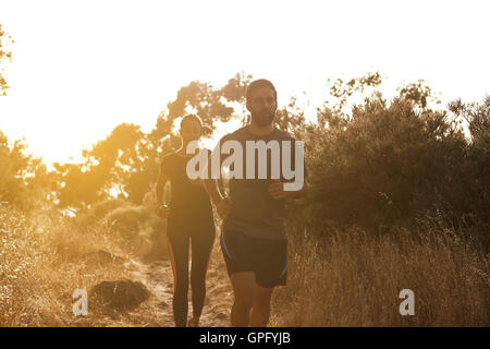 Running young couple in shadows with sun light behind them while