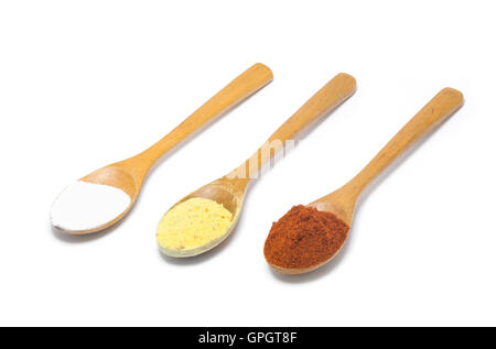 three common spices in wooden spoons isolated on white background. Stock Photo