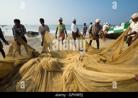 Fishermen repairing their huge nets for catching fishes the traditional way. Stock Photo