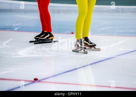 legs of two girls speed skaters at starting line during competition in speed skating Stock Photo