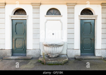 Old style public toilet for men and women with green painted doors and writing in German language. Stock Photo