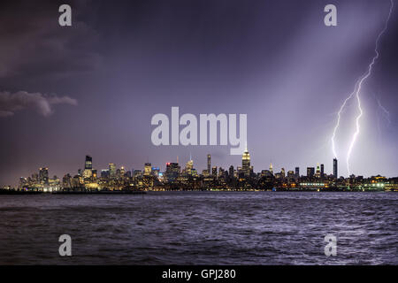 Lightning hitting a New York City skyscraper at twilight. Stormy skies over Midtown West Manhattan from the Hudson River Stock Photo