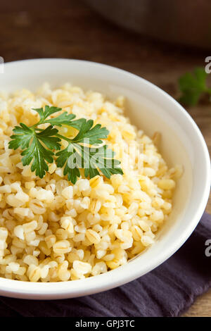 Organic bulgur wheat grain in white bowl close up, healthy vegetarian food Stock Photo