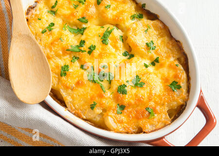 Potato gratin (casserole) with cream, cheese and parsley in baking dish Stock Photo