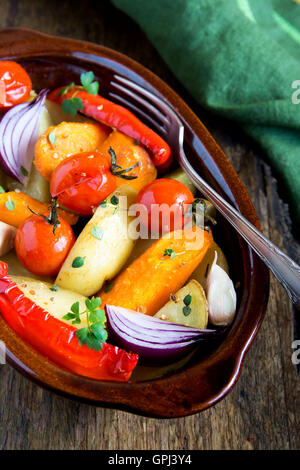 Rustic oven baked vegetables with spices and herbs in baking dish close up, vegetarian organic healthy meal Stock Photo
