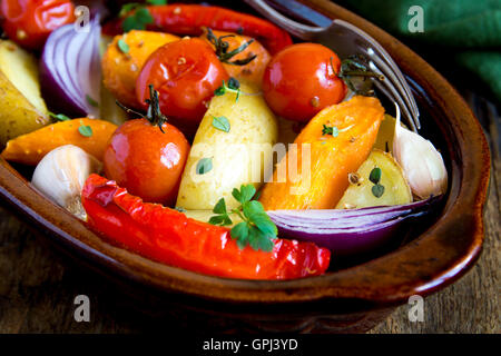 Rustic oven baked vegetables with spices and herbs in baking dish close up, vegetarian organic healthy meal Stock Photo