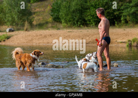 man is playing with dogs in a river Stock Photo