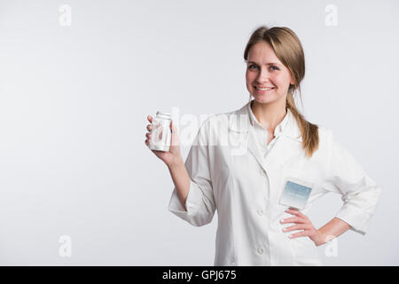 Young smiling female doctor presenting a white unlabeled bottle or recipient of pills Stock Photo