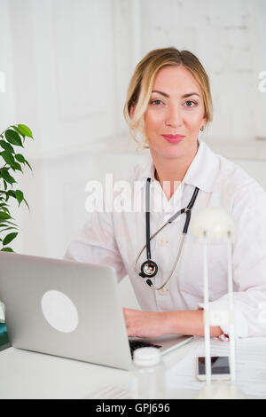 Portrait Of Happy Young Female Doctor Working On Computer at her office Stock Photo