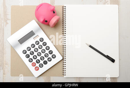 a piggy bank, calculator and notepad on a table Stock Photo