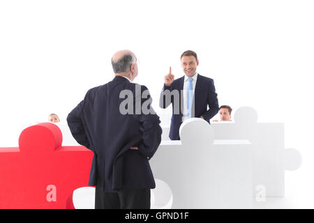 Business people hiding behind puzzle pices Stock Photo