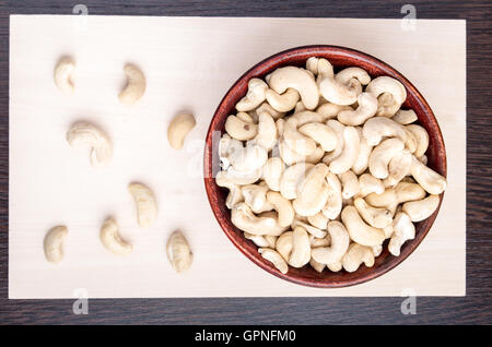 Top view on raw cashew nuts for vegetarian food in a small wooden bowl on a wooden board. Stock Photo