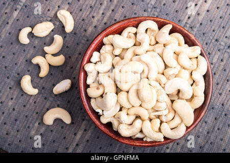 Selective focus on at the tasty and healthy raw cashew nuts in a brown bowl on fabric background Stock Photo