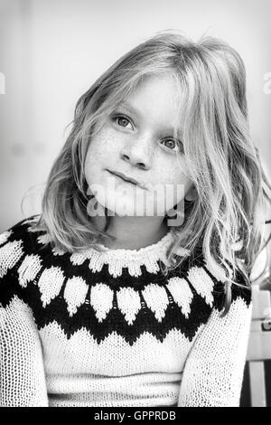 Young girl with a messy hair and wearing a sweater.
