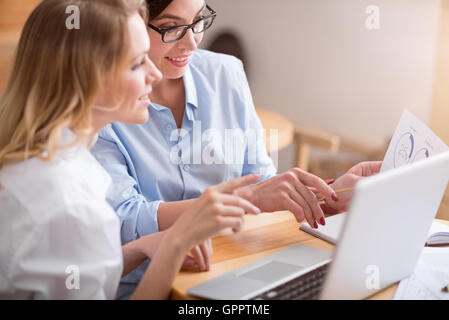 Two female colleagues using laptop Stock Photo