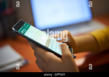 Young woman using cell phone to send text message on social network at night. Closeup of hands Stock Photo